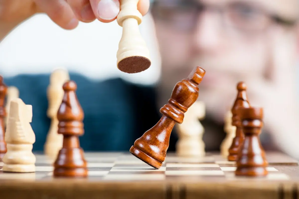 A dramatic image of a queen knocking over a king on a chessboard, symbolizing a dominant victory