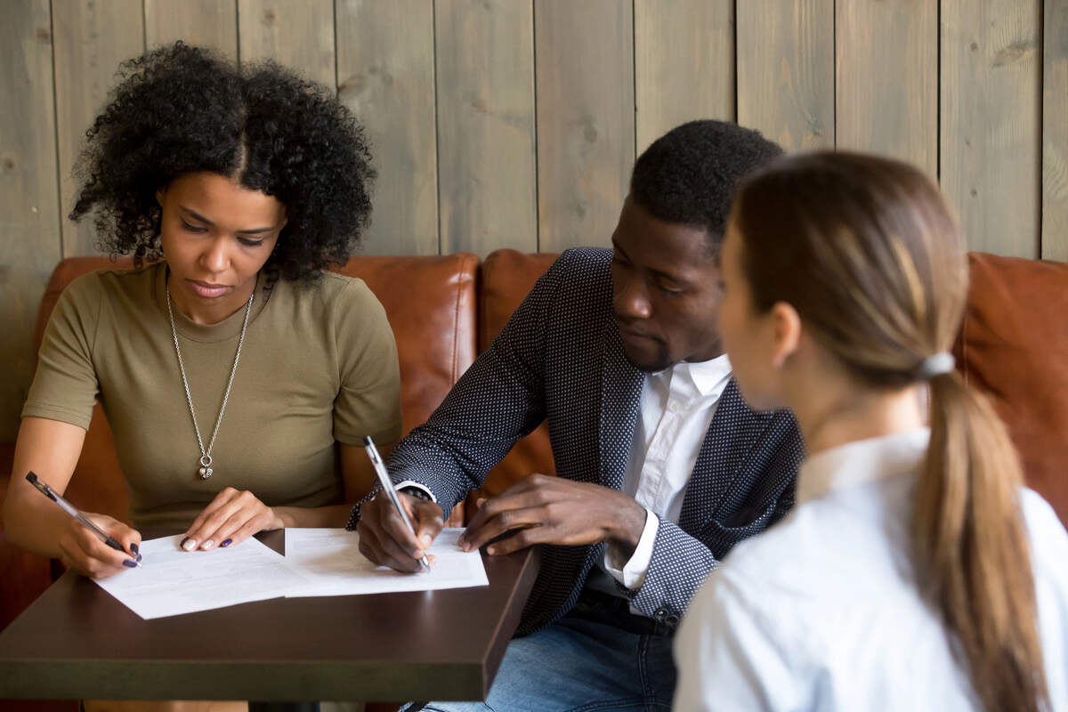 A family lawyer helps a young couple understand a document they are signing together.