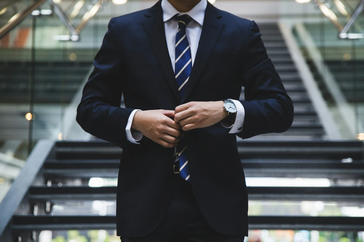 A well dressed male attorney adjusts the buttons on his suit