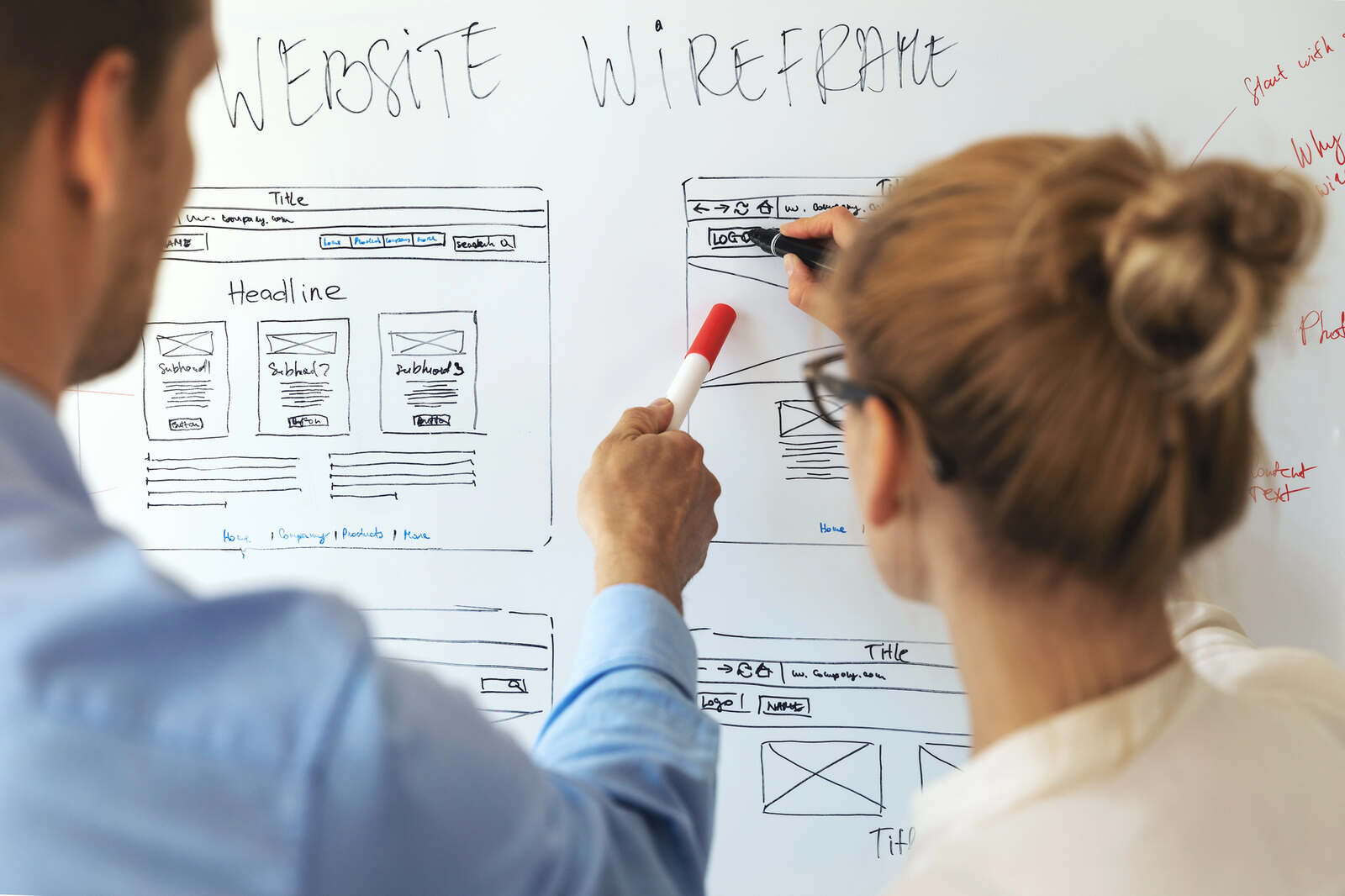 A male and a female web designer working together to mock up a new law firm website design on a whiteboard.