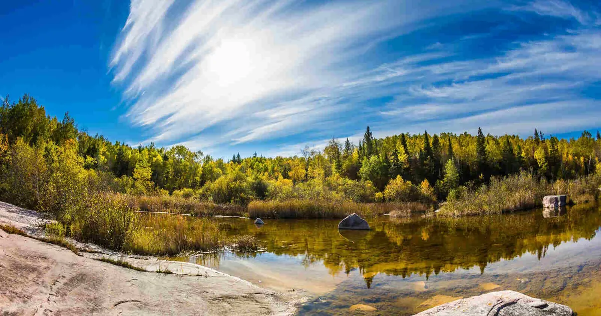 Old Pinawa Dam Park on a sunny day, with the Winnipeg River in the foreground