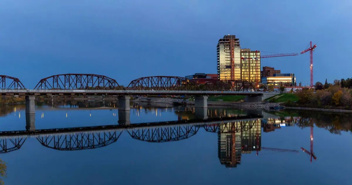 A bridge over the river in downtown Saskatoon, reflected in calm water at dawn