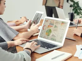 A laptop screen displays a dashboard containing various SEO metrics, with colourful charts and graphs