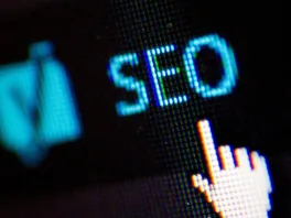 A mouse pointer hovers over the letters "SEO" on a black screen