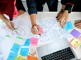 sticky notes and design wireframes spread across an office table