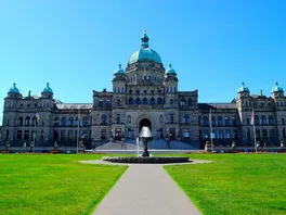 The main block British Columbia parliament buildings stands majestically over a perfectly green lawn in Victoria, British Columbia